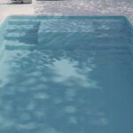 Piscine extérieure avec reflets d'arbres et ciel.