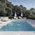 Piscine extérieure avec fauteuils et parasols blancs.